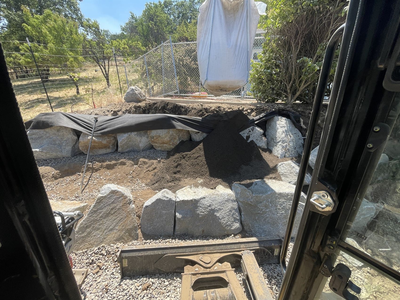 Boulder and stone edge work being built around a pond in the Rogue Valley