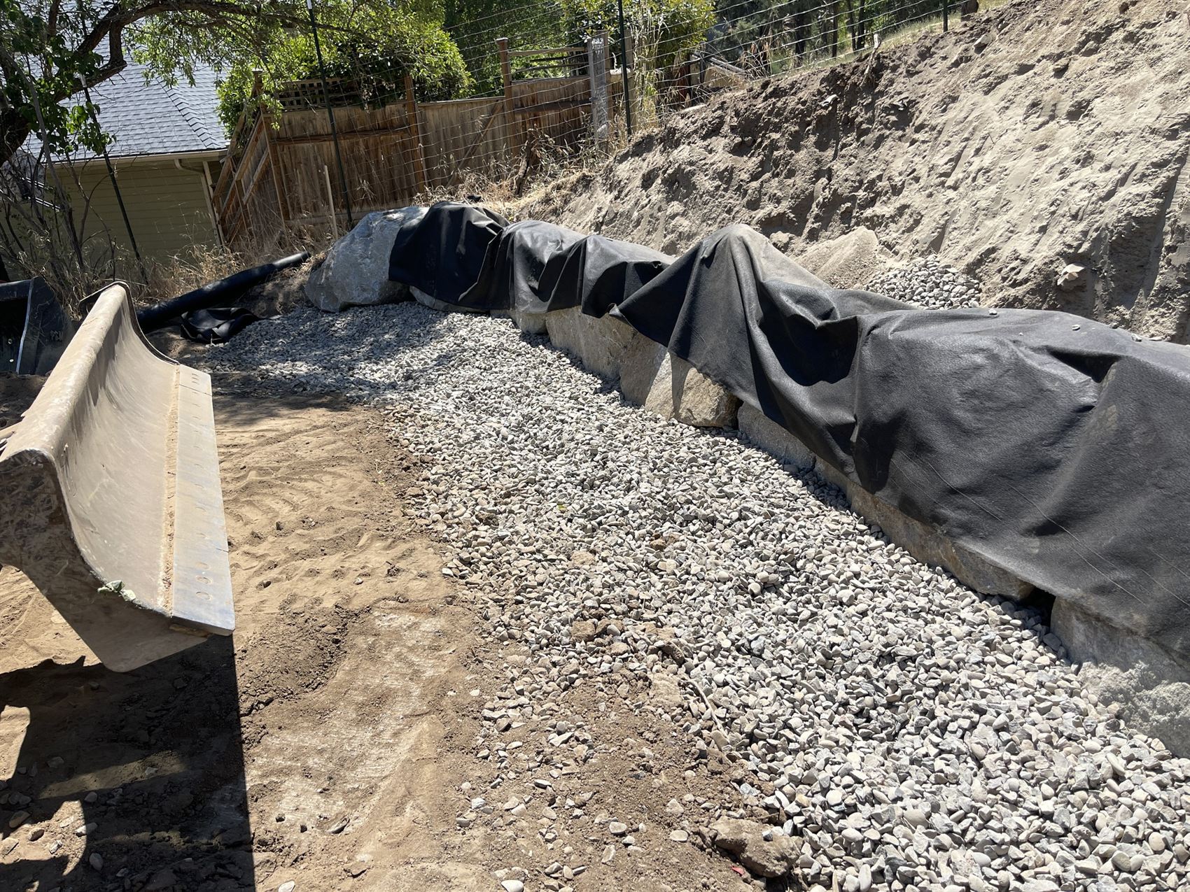 Boulder retaining wall with drain rock and filter-fabric drainage installed by Pacific Earthworks in the Rogue Valley