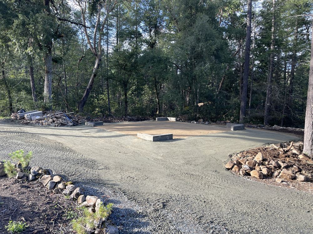 Compacted gravel building pad with concrete footings prepared on a wooded lot