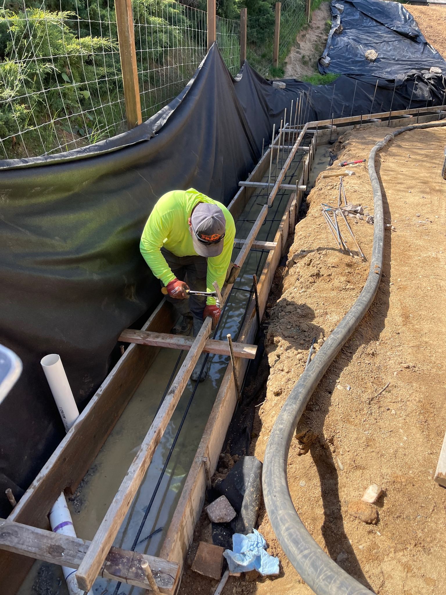 Worker setting formwork and rebar for a concrete foundation footing in Southern Oregon