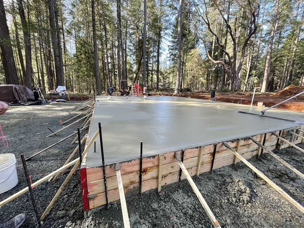 Freshly poured concrete slab foundation with forms among the pines