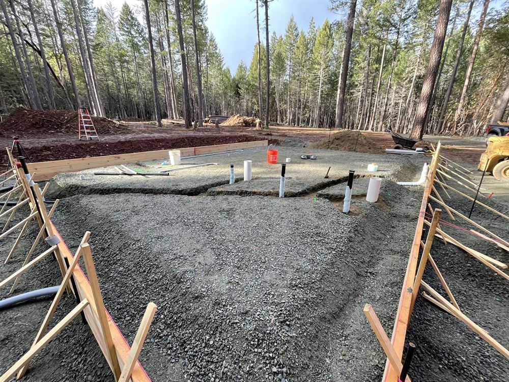 Custom home foundation footings and gravel pad prepared in a forest setting