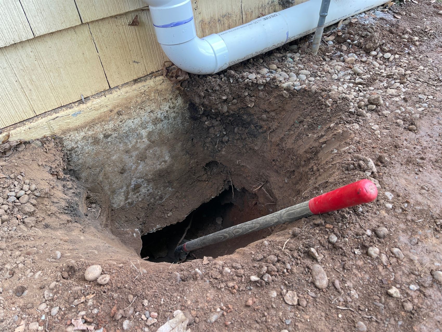 Utility and drainage line connection excavated at the corner of a home
