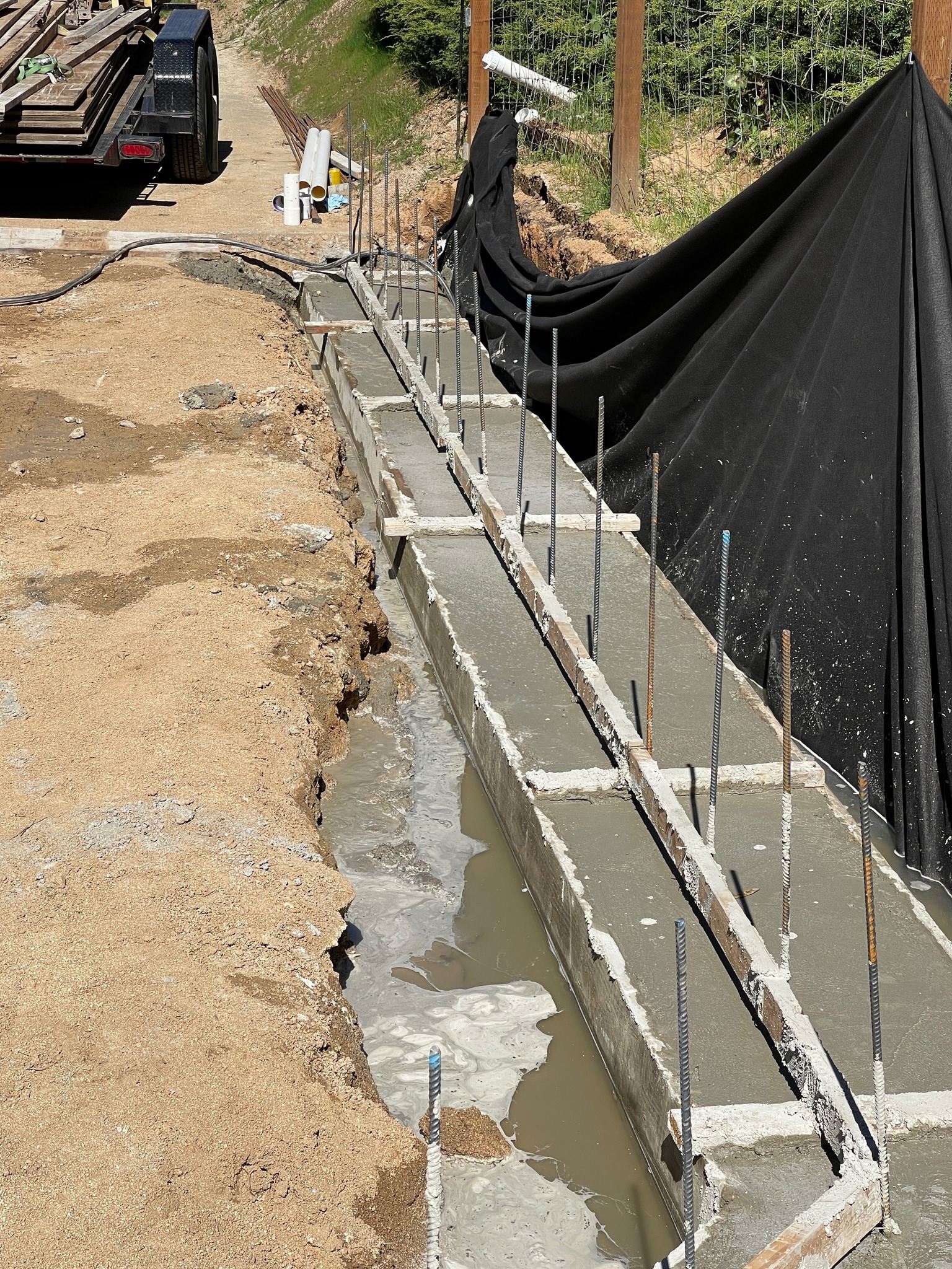 Concrete foundation footing with rebar freshly poured on a hillside by Pacific Earthworks