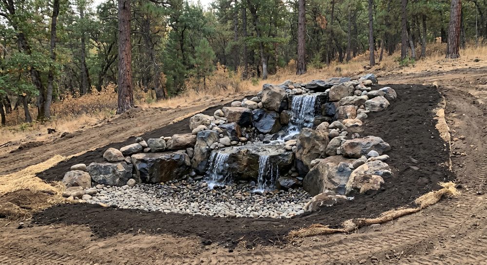 Pondless waterfall construction with boulders and hidden gravel basin in Southern Oregon