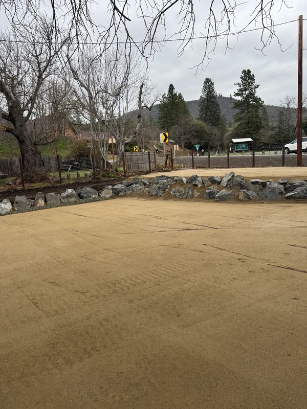 Finished decomposed-granite lot with a boulder border seen from the highway in Jacksonville, Oregon