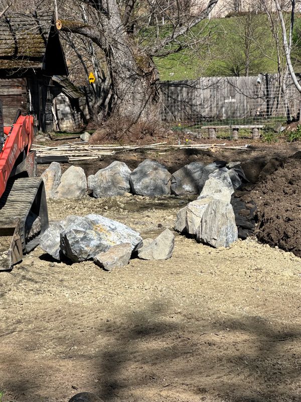 Skid steer placing decorative boulders along the graded yard in Jacksonville, Oregon
