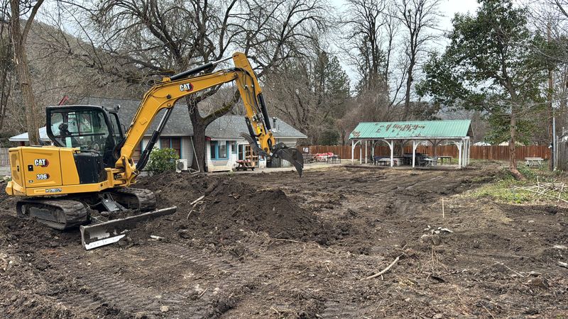 Pacific Earthworks excavator stripping and grubbing the lot during commercial site prep in Jacksonville, Oregon