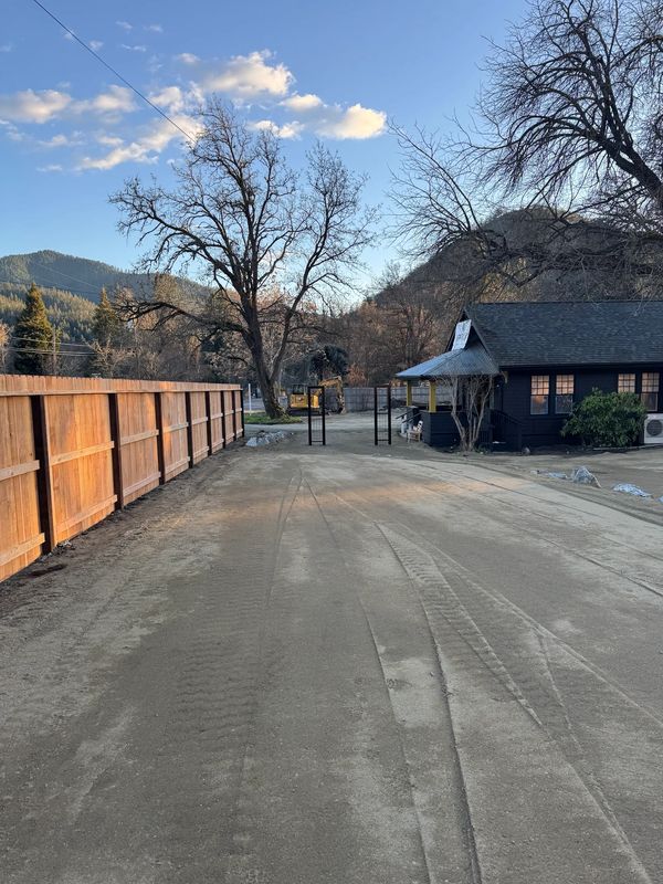 Graded gravel access drive along a new cedar fence during commercial site prep in Jacksonville, Oregon