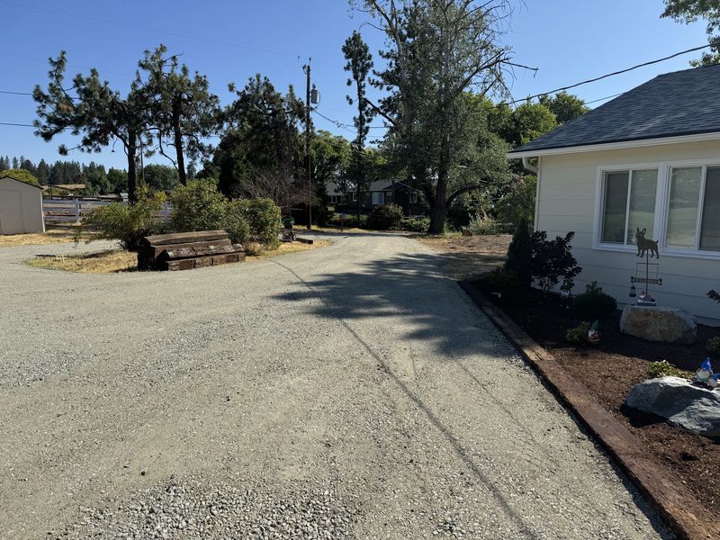 Freshly regraded and compacted gravel driveway running alongside a rural home in the Rogue Valley, Oregon