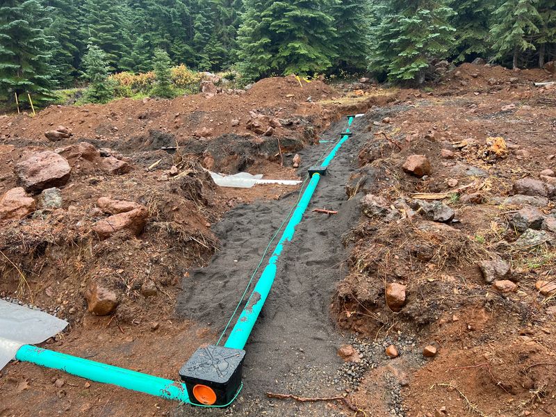 Septic drainfield distribution lines and distribution boxes bedded in sand during a high-elevation septic installation in Southern Oregon