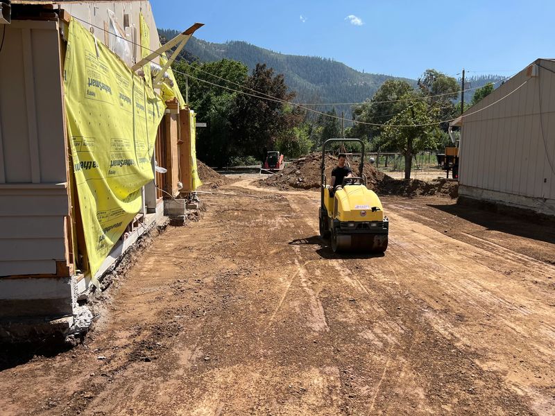 Ride-on roller compacting graded soil between a custom home and shop in the Applegate Valley, Oregon